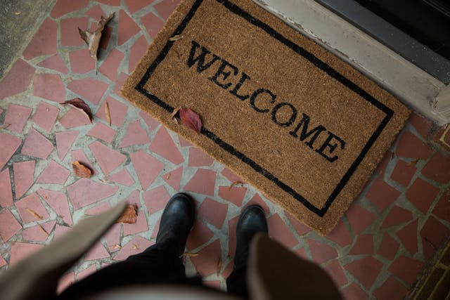 A person wearing shoes standing at a "Welcome" door mat